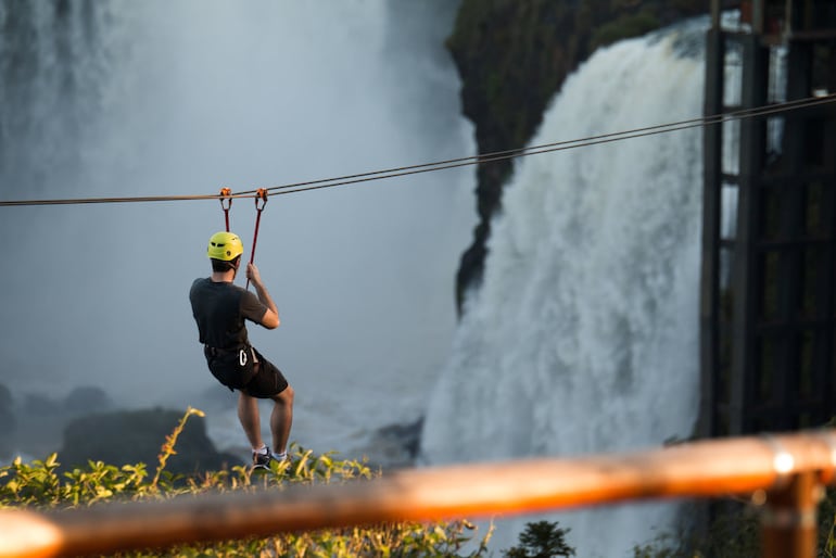 Un joven realiza tirolesa frente al imponente Salto Monday. 