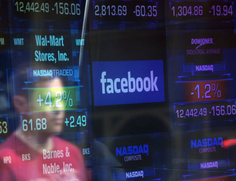 (FILES) In this file photo taken on May 17, 2012 a Facebook logo is seen through the windows of the NASDAQ stock exchange as people walk by on Times Square in New York. - Key chapters in the history of Facebook, the world's biggest social media application, which marks the tenth anniversary Wednesday of its stock market debut. Facebook boss Mark Zuckerberg rang the opening bell remotely to cheers 10 years ago as the beloved social network made its stock market debut, culminating an all-night hackathon that included street hockey, costumes and music. The Silicon Valley tech colossus rebranded as Meta has since seen its image tainted by accusations it has become a tech tyrant, putting profit over user privacy and even the good of society.