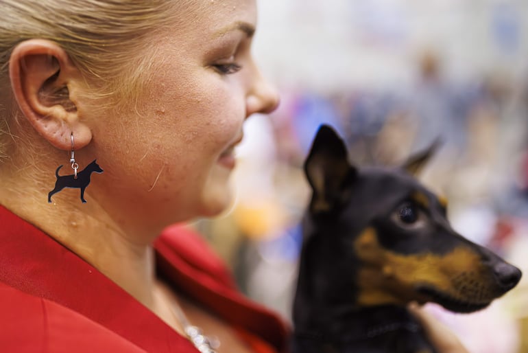 Una mujer con pendientes a juego con la raza de su perro durante el Concurso Mundial de Perros que se celebra en Ginebra, Suiza.