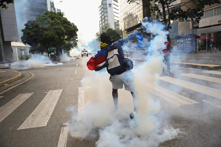 Protestas en Venezuela: un manifestante arroja el gas lacrimógeno de vuelta a la policía, 29 de julio de 2024 (Foto: Raúl Arboleda / AFP)