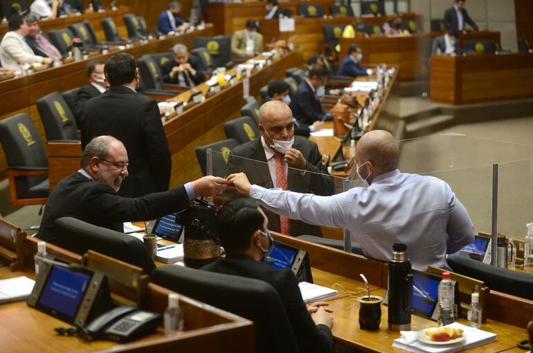 Los diputados cartistas  Justo Zacarías Irún (investigado) y Hugo Ramírez (d) hacen el gesto de complicidad después de atropellar el reglamento interno para que una colorada ocupe una banca.