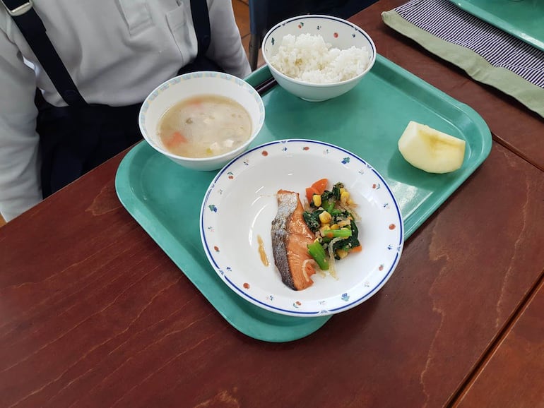 Sopa (en este caso miso), arroz y proteína (salmón con verduras variadas) y una porción de fruta son parte de un almuerzo escolar japonés. A esto se suma leche. 