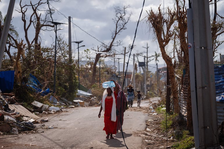 Una mujer lleva agua en Pamandzi, en el territorio francés de Mayotte en el Océano Índico, el 17 de diciembre de 2024, tras el paso del ciclón Chido por el archipiélago.