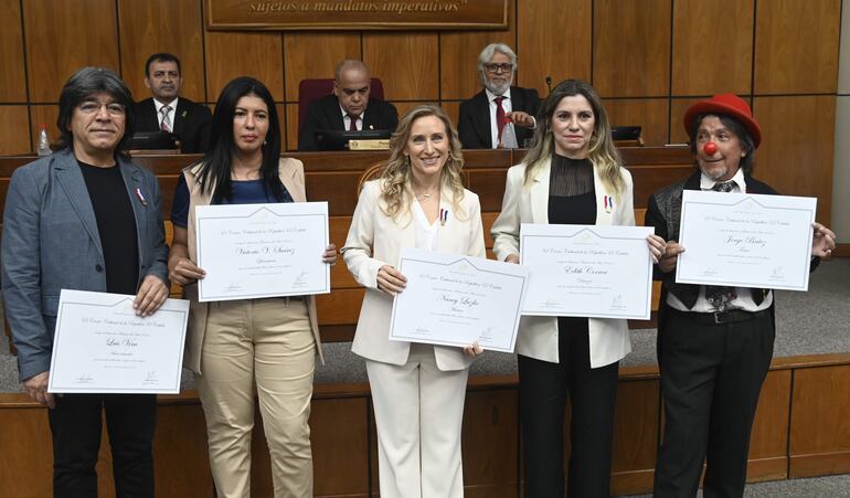 Luis Vera, Dominga Vega en representación de Victorio Suárez, Nancy Luzko, Edith Correa, y Jorge "Bochín" Brítez posan con sus reconocimientos como Maestros del Arte 2024.