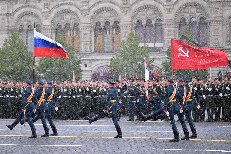 Soldados de la guardia de honor rusa que portan la bandera nacional rusa y una bandera roja, réplica de la pancarta de la Victoria, marchan en la Plaza Roja durante el desfile militar del Día de la Victoria en Moscú .