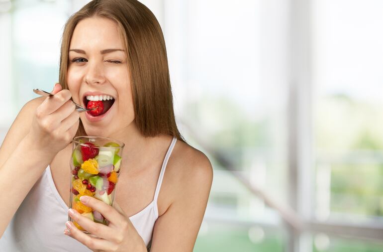 Mujer comiendo frutas.