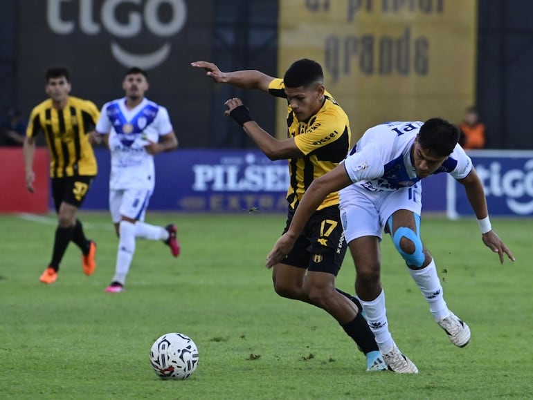 Brahian Fernández, jugador de Guaraní, pelea el balón con el futbolista de Ameliano, Diego Barreto.