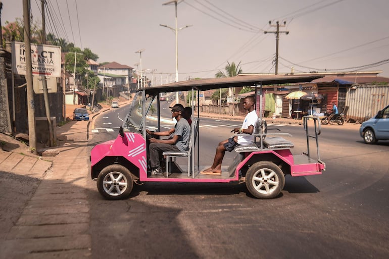 El innovador autodidacta James Samba (izquierda) conduce un vehículo eléctrico ecológico que fabricó con metales reciclados en Freetown.