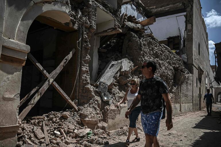 Turistas caminan junto a un edificio destrozado en Marrakech.