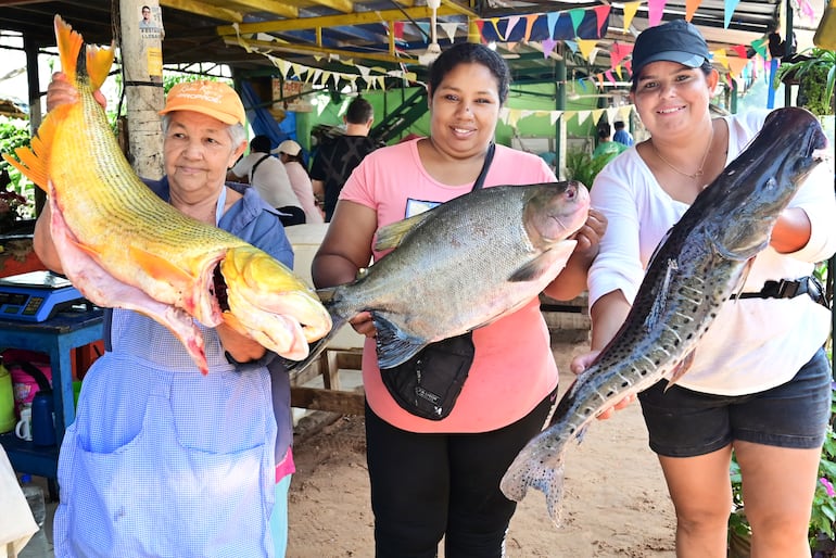 Comerciantes de Remanso mostrando ejemplares de pescado tipo dorado, pacú y surubí, en ese orden.