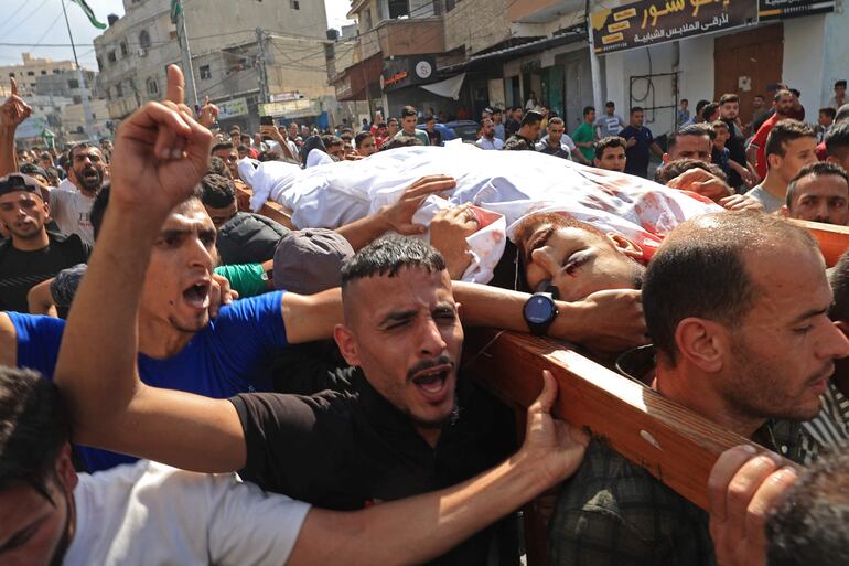 Palestinos cargan el cuerpo de una persona muerta por una ataque israelí en represalia en Khan Yunis, luego del ataque de Hamás a la Franja de Gaza. 