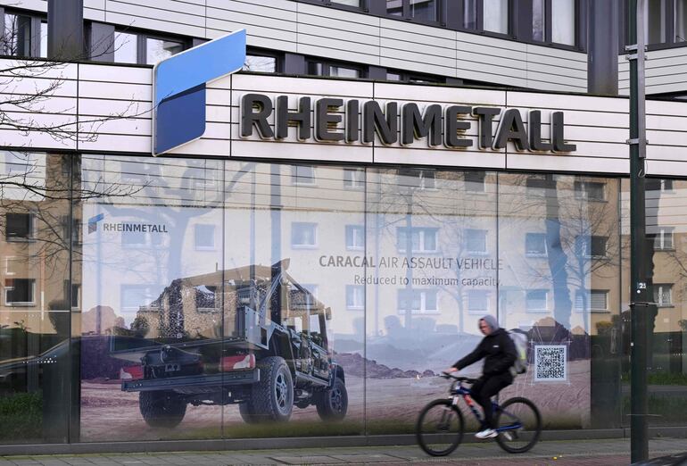 Un ciclista pasa junto a un anuncio en la sede del productor de armas y proveedor de automóviles alemán Rheinmetall.