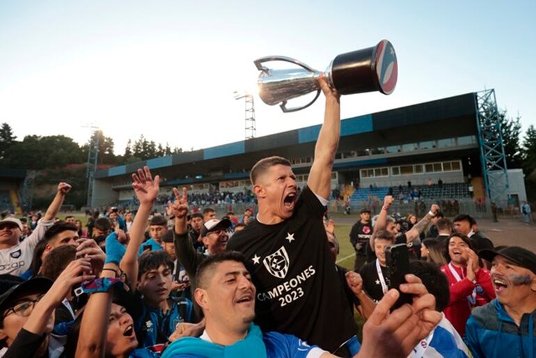 Cris Martínez levanta el trofeo de campeón llevando en andas por aficionados del Huachipato dentro del campo de juego. El delantero paraguayo fue la figura del equipo en la conquista del título. (Foto El Mercurio).