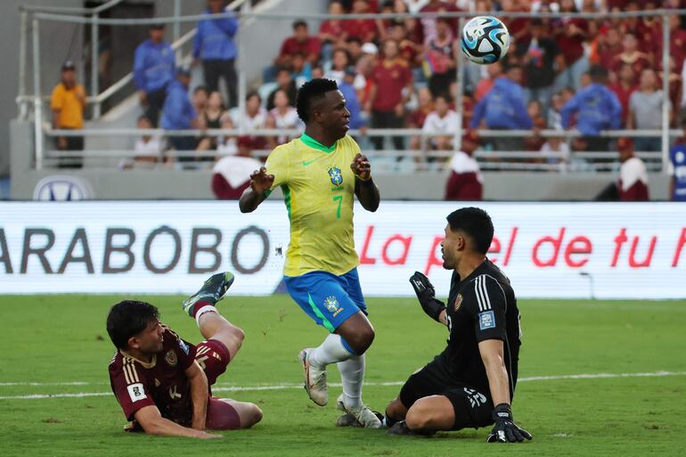 AMDEP9689. MATURÍN (VENEZUELA), 12/11/2024.- Rafael Romo (d) de Venezuela disputa el balón con Vinícius Jr. de Brasil, este jueves durante un partido de las eliminatorias sudamericanas al Mundial de Fútbol 2026, en el estadio Monumental, en Maturín (Venezuela). EFE/ Miguel Gutiérrez
