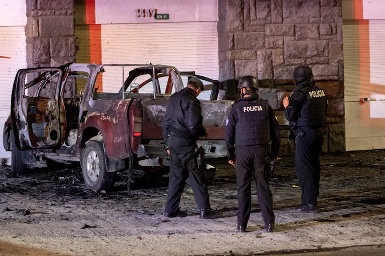 Policías investigan los restos de un carro bomba que explotó en la madrugada en los exteriores del edificio del Servicio Nacional de Atención Integral a Personas Privadas de Libertad (SNAI), en Quito (Ecuador).