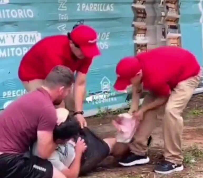 Momento en el que empleados y un tercero extraen la carne de debajo de las prendas de un hombre.