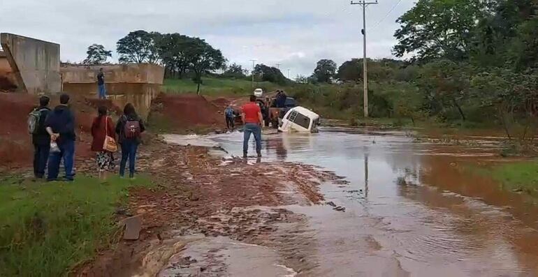 Varias personas ayudan a sacar la camioneta del arroyo Capiibary.