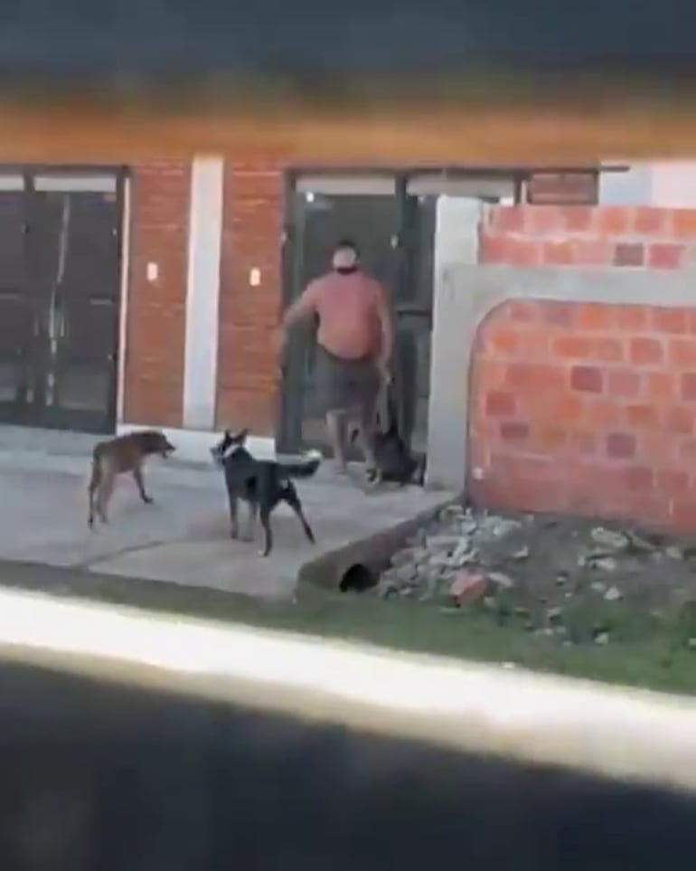 El hombre con el perro muerto en la mano, luego de haberlo degollado.