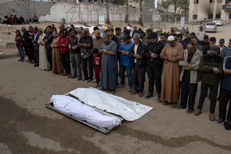 Un grupo de personas reza sobre los cuerpos de dos fallecidos a causa de un bombardeo israelí, este sábado en Jan Yunis.
