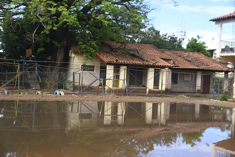 En el fondo, se observa el pabellón clausurado por riesgo de derrumbe en Delfín Chamorro, ubicada tras la cancha que quedó inundada por la lluvia caída entre ayer y hoy.