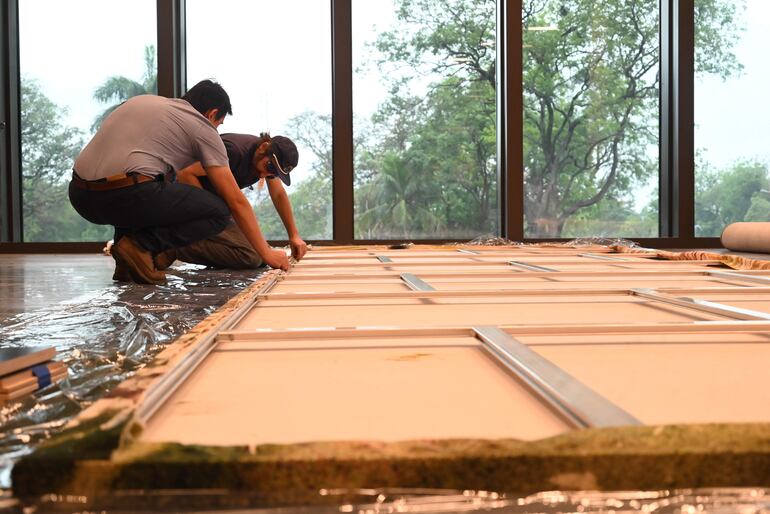 Grupo de montadores ultimando detalles antes de colgar una de las obras de gran formato.