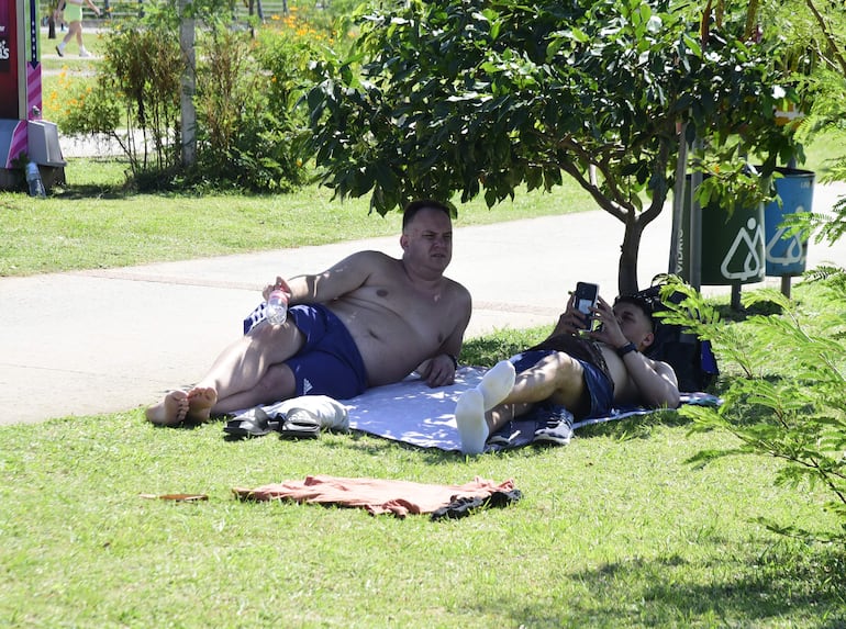 Hinchas argentinos se rebuscaban para guarecerse del calor en las escasas sombras que encontraron en la Costanera Norte de Asunción.