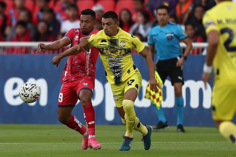 Ángel Gracia (i), futbolista de El Nacional, disputa el balón con Joel Román, jugador de Sportivo Trinidense, en un partido de la Fase 2 de la Copa Libertadores en el estadio Rodrigo Paz Delgado, en Quito, Ecuador.