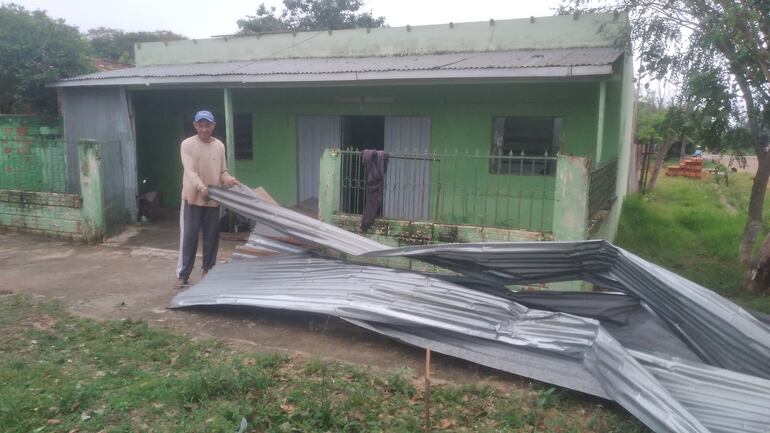 Carlos Quiroga, acomodando las chapas que hizo volar el temporal en Coronel Oviedo.