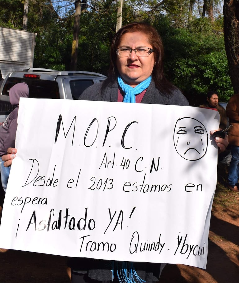 La docente Mirian Barrios, con su pancarta para exigir Asfaltado Ya.