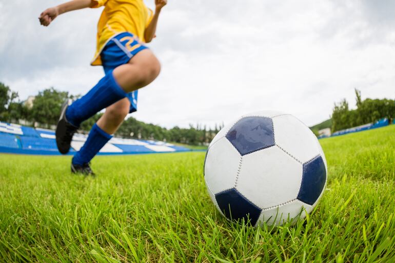 Un niño se apresta a patear una pelota de fútbol.