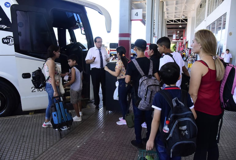 Familias enteras aguardan en fila para subir a un bus en la Estación de Buses.