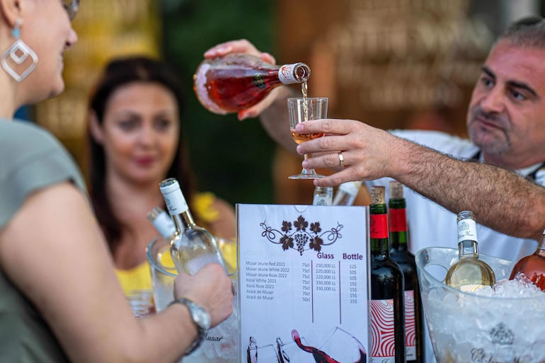 A man serves a a glass of local wine during the fifth annual wine festival in the town of Dhour Shweir in Lebanon's Matn district on July 20, 2024.  (Photo by Khaled DESOUKI / AFP)