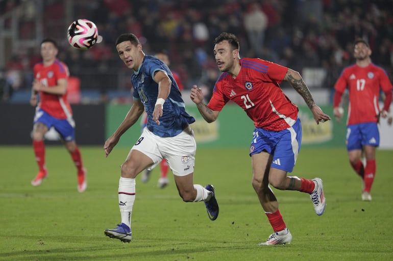 Alex Arce (i), jugador de la selección paraguaya, pelea por el balón con Matías Catalán, futbolista de Chile, en un partido amistoso internacional en el estadio Nacional, en Santiago, Chile).