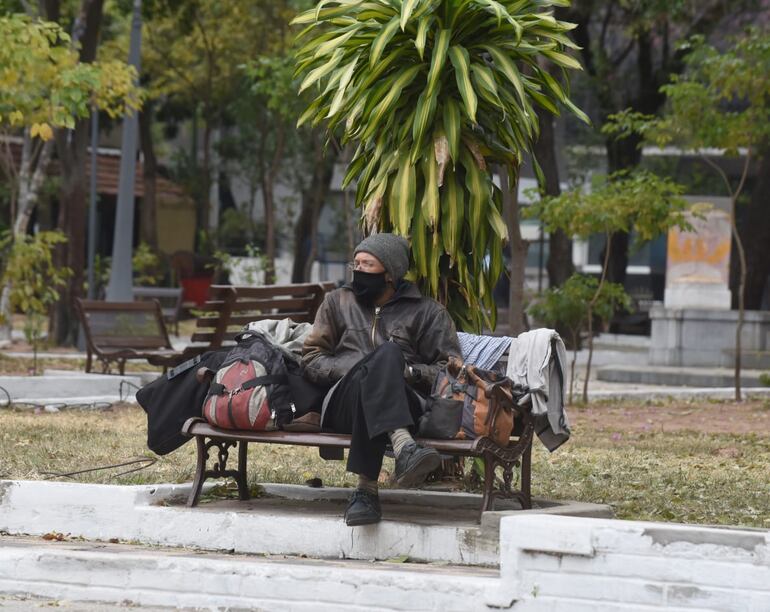 Imagen de archivo y referencia: un hombre abrigado sentado en una plaza de Asunción.