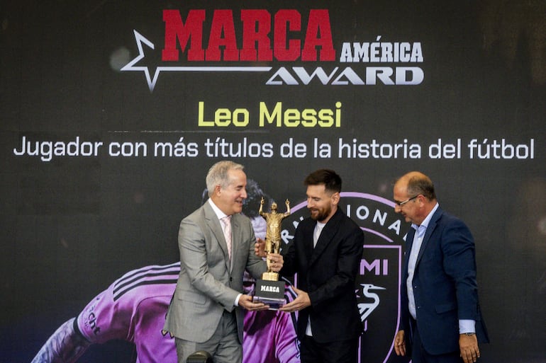 El dueño del Inter Miami, Jorge Más, entrega el trofeo del Premio Marca América a Lionel Messi junto al director del diario Marca, Juan Ignacio Gallardo. (EFE/ Eva Marie Uzcátegui)
