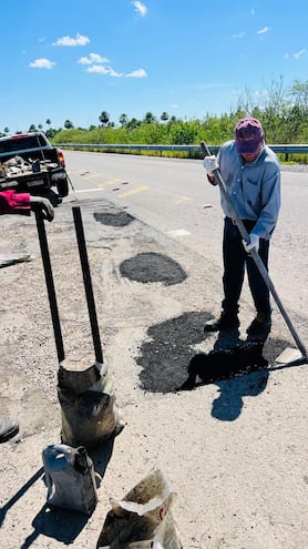 Un funcionario del distrito N° 12 del MOPC realiza el bacheo con asfalto en frio en el km 29 de la ruta PY19 con herramientas rudimentarias.