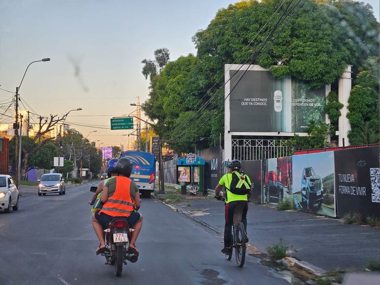 A la derecha se ve a un ciclista correctamente equipado con chaleco reflectivo y casco, pedaleando su bicicleta sobre la avenida España de Asunción.