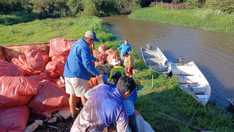 Los voluntarios de la Asociación de Pescadores alzan en un camión volquete los desechos recolectados del Tapiracuai.