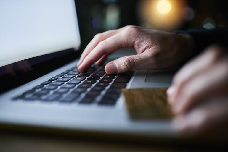 Una persona realiza compras en línea en su computadora laptop con una tarjeta de crédito en la mano.