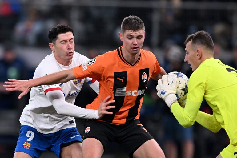 Robert Lewandowski (i), delantero del Barcelona, en acción contra Valeriy Bondar y Dmytro Riznyk, zaguero y arquero del Shakhtar Donetsk, durante el partido que el equipo ucraniano derrotó al Barcelona por la Champions League.