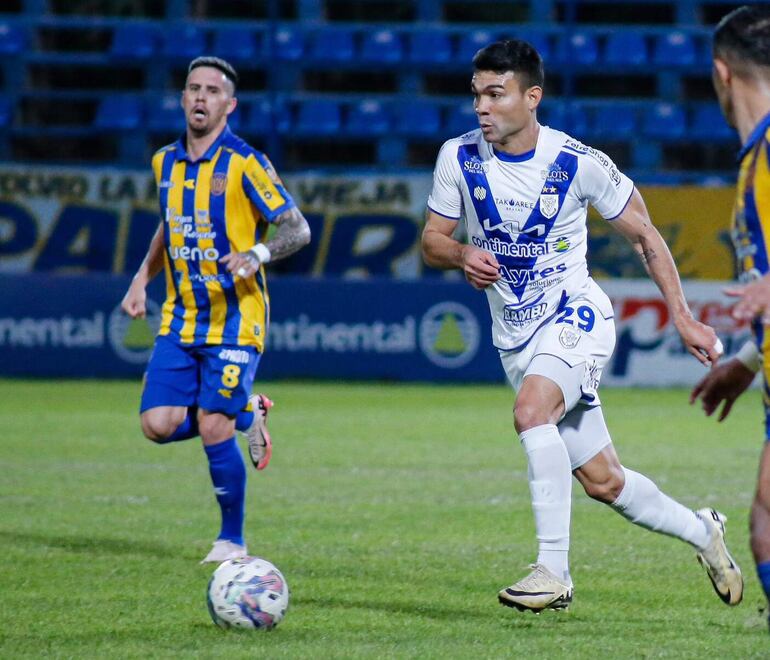 El delantero de Ameliano Iván Valdez, se lleva el balón en ataque ante la mirada de Jorge Mendoza.