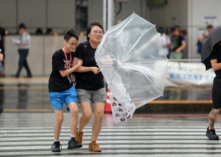 Transeúntes con paraguas luchan contra el viento este viernes en Tokio.
