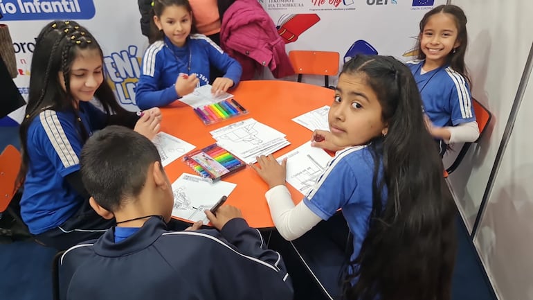 Niños que visitan la libroferia se divierten coloreando las postales “Pintando Encarnación”.