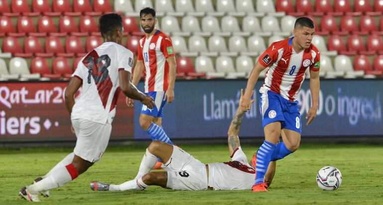 Richard Sánchez (d), jugador de la selección paraguaya, domina el balón frente a la marca de los peruanos en un partido por la primera fecha de las Eliminatorias Sudamericanas al Mundial Qatar 2022 en el estadio Defensores del Chaco.