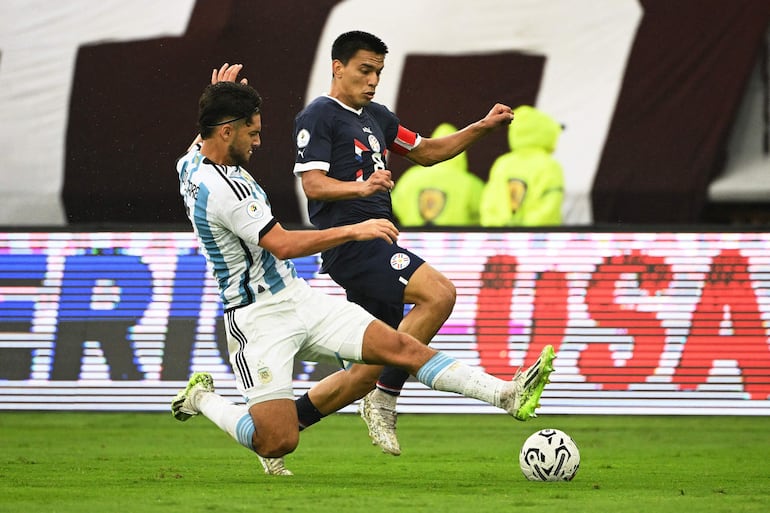 El argentino Marco Di Cesare (i) y el paraguayo Diego Gómez (d) luchan por el balón durante el partido de fútbol del Torneo Preolímpico CONMEBOL Venezuela 2024 entre Argentina y Paraguay en el estadio Brígido Iriarte de Caracas el 8 de febrero de 2024.