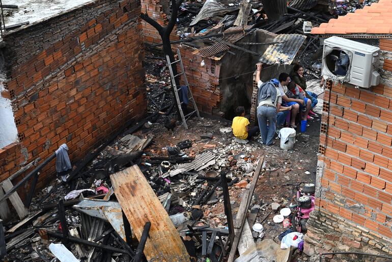 Familias afectadas retornaron esta mañana a la Chacarita para revisar el lugar donde estaba su casa. En la foto, un hombre con niño en brazos, mujer y niños sentados.