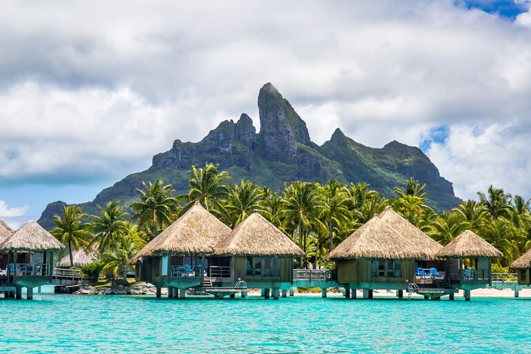 Un paisaje maravilloso de mar, montaña y bungalows en la Polinesia Francesa.