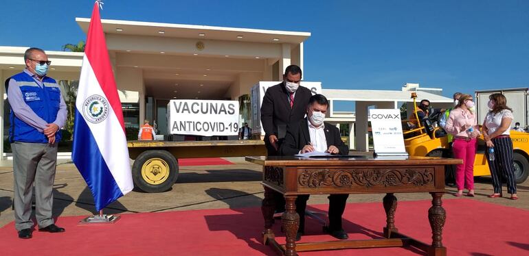 Julio Borba, ministro de Salud, firmando documentos tras recibir un lote de vacunas del mecanismo Covax. 