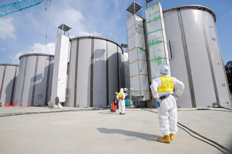 Trabajadores con trajes de protección ante los tanques de almacenamiento de agua radiactiva en la central nuclear de Fukushima, Japón, en marzo de 2014.