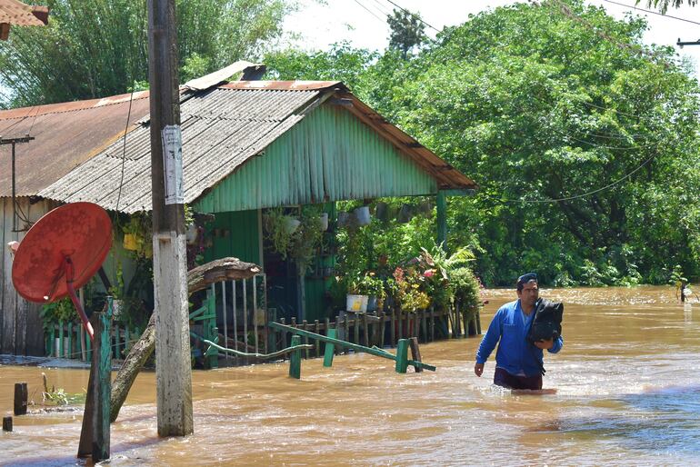 Un hombre con la mitad del cuerpo metido en el agua ingresa a lugar alto de la zona anegada.